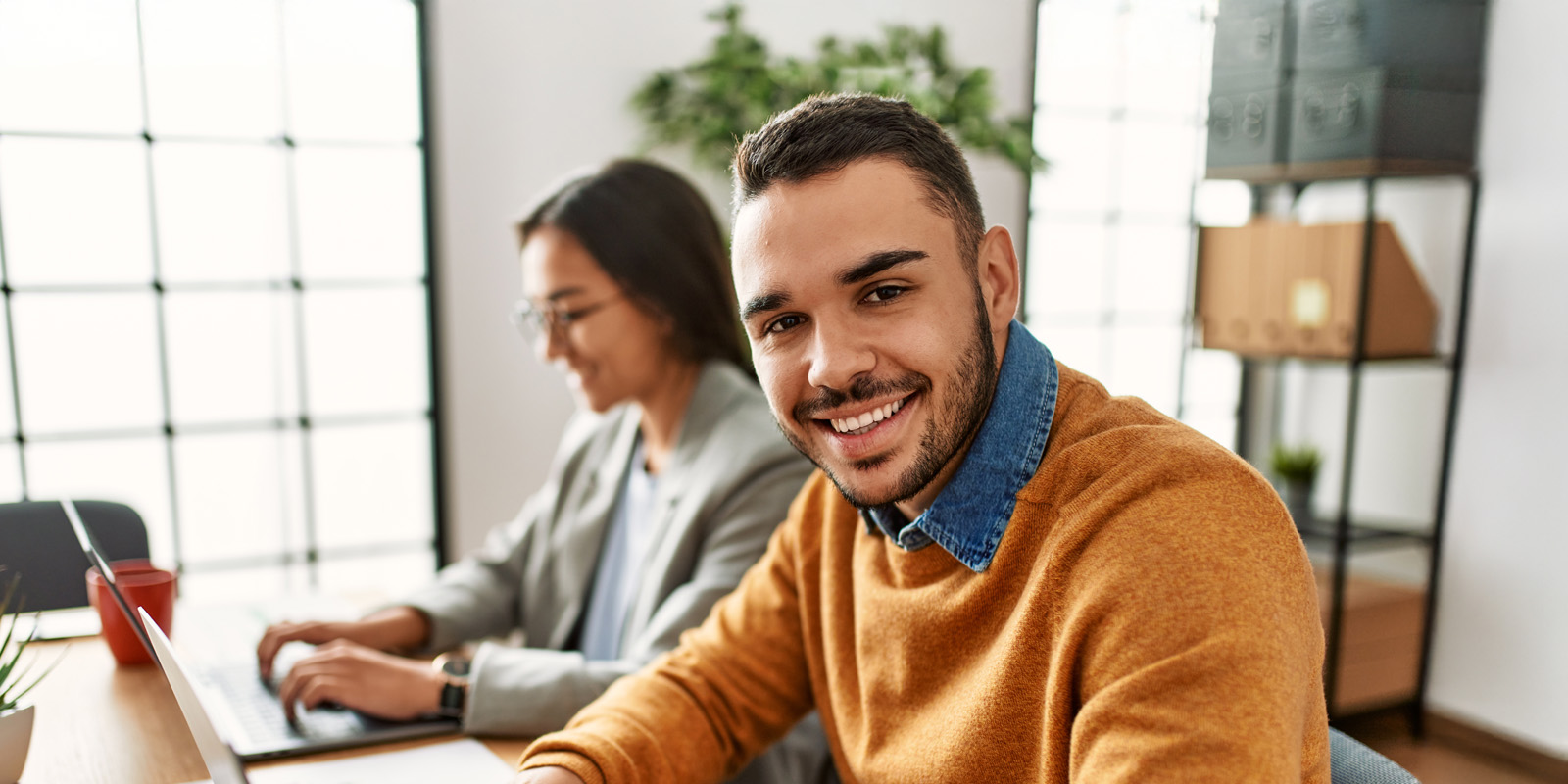 Brown man and woman at laptops.